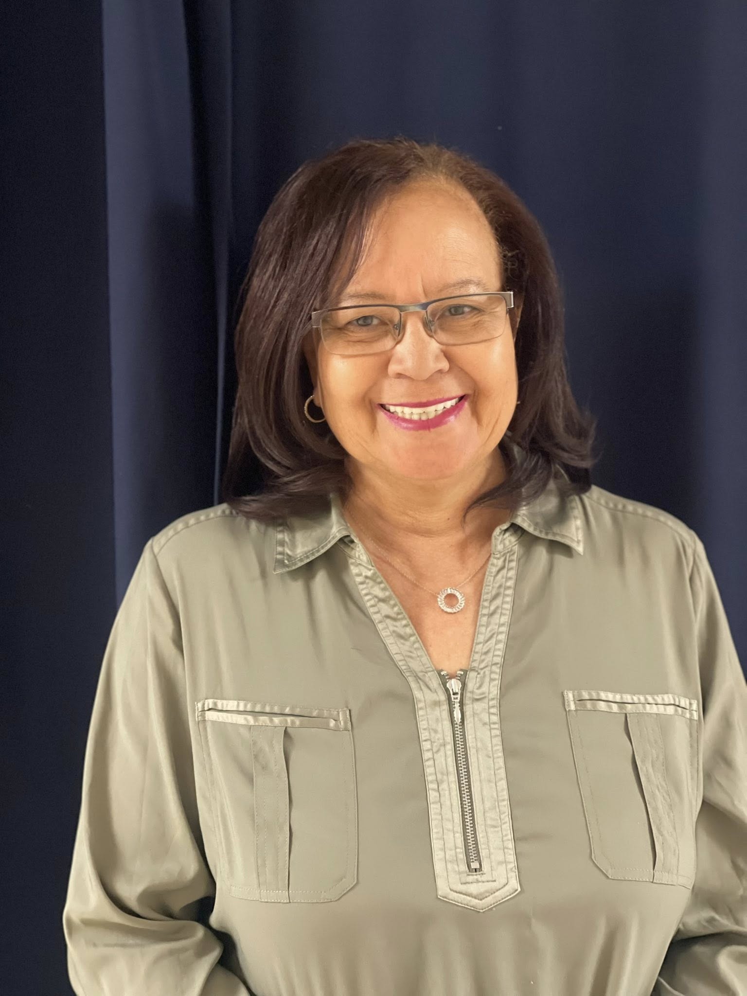 A photo of a smiling woman with a bob haircut and wearing glasses.